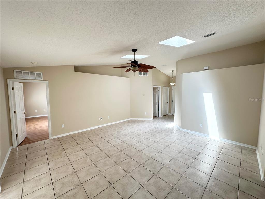 A spacious room with beige walls, tile flooring, a ceiling fan, and two skylights — 36 PORT ROYAL DRIVE, PALM COAST, FL