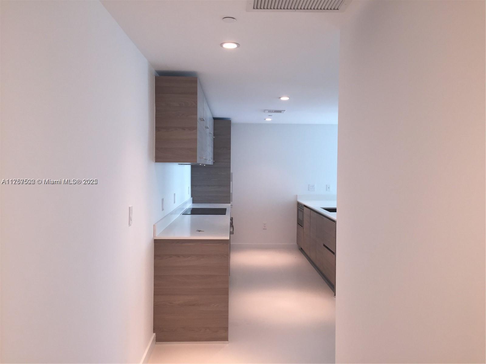 A galley-style kitchen features wood-grain cabinetry, white countertops, and recessed lighting — 1300 S Miami Ave # 1910, Miami FL 33130, MIAMI, FL