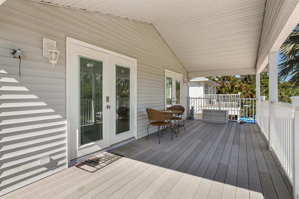 A covered wooden deck features a small bistro set and double glass doors — 2804 AVENUE C, HOLMES BEACH, FL
