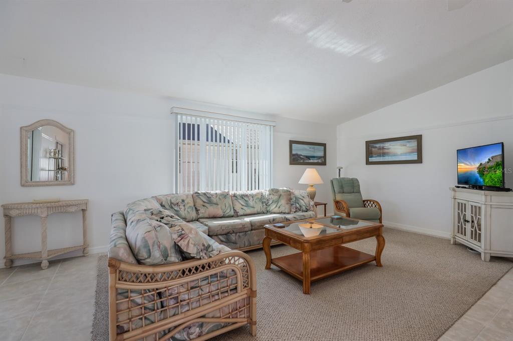 A living room features a floral sectional sofa, a wooden coffee table, and a television — 2804 AVENUE C, HOLMES BEACH, FL