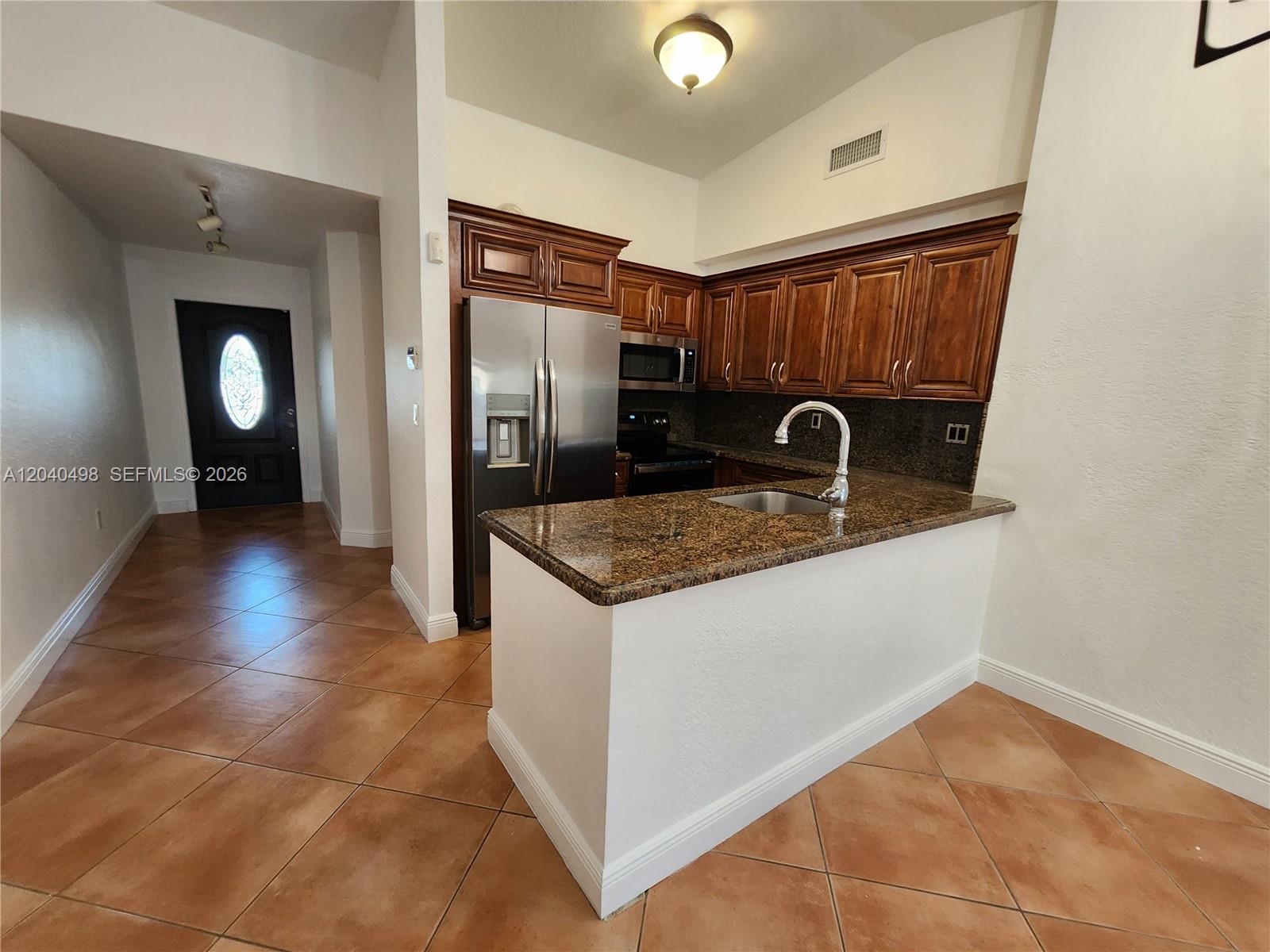 A kitchen features wood cabinets, granite countertops, stainless steel appliances, and tile flooring — 13412 SW 17th Terr Cir S, Miami FL 33175, MIAMI, FL