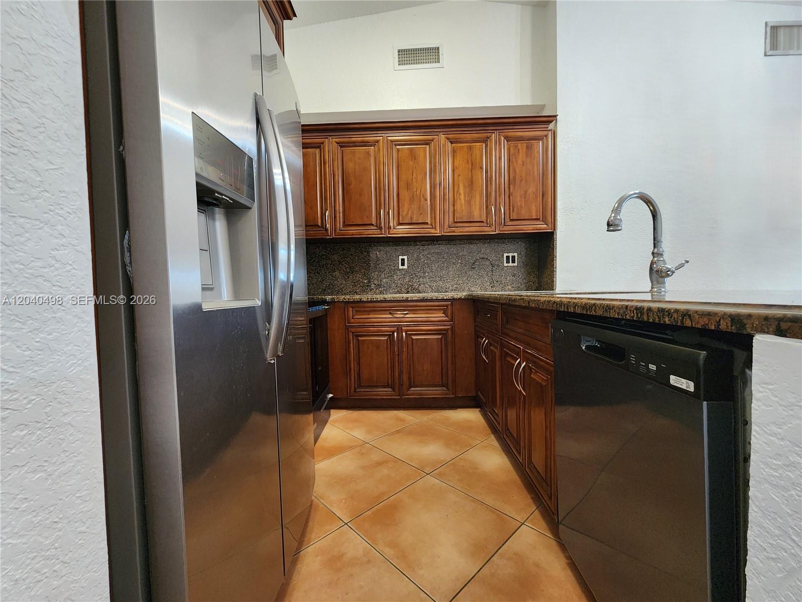 A kitchen features dark wood cabinets, granite countertops, stainless steel appliances, and tiled flooring — 13412 SW 17th Terr Cir S, Miami FL 33175, MIAMI, FL