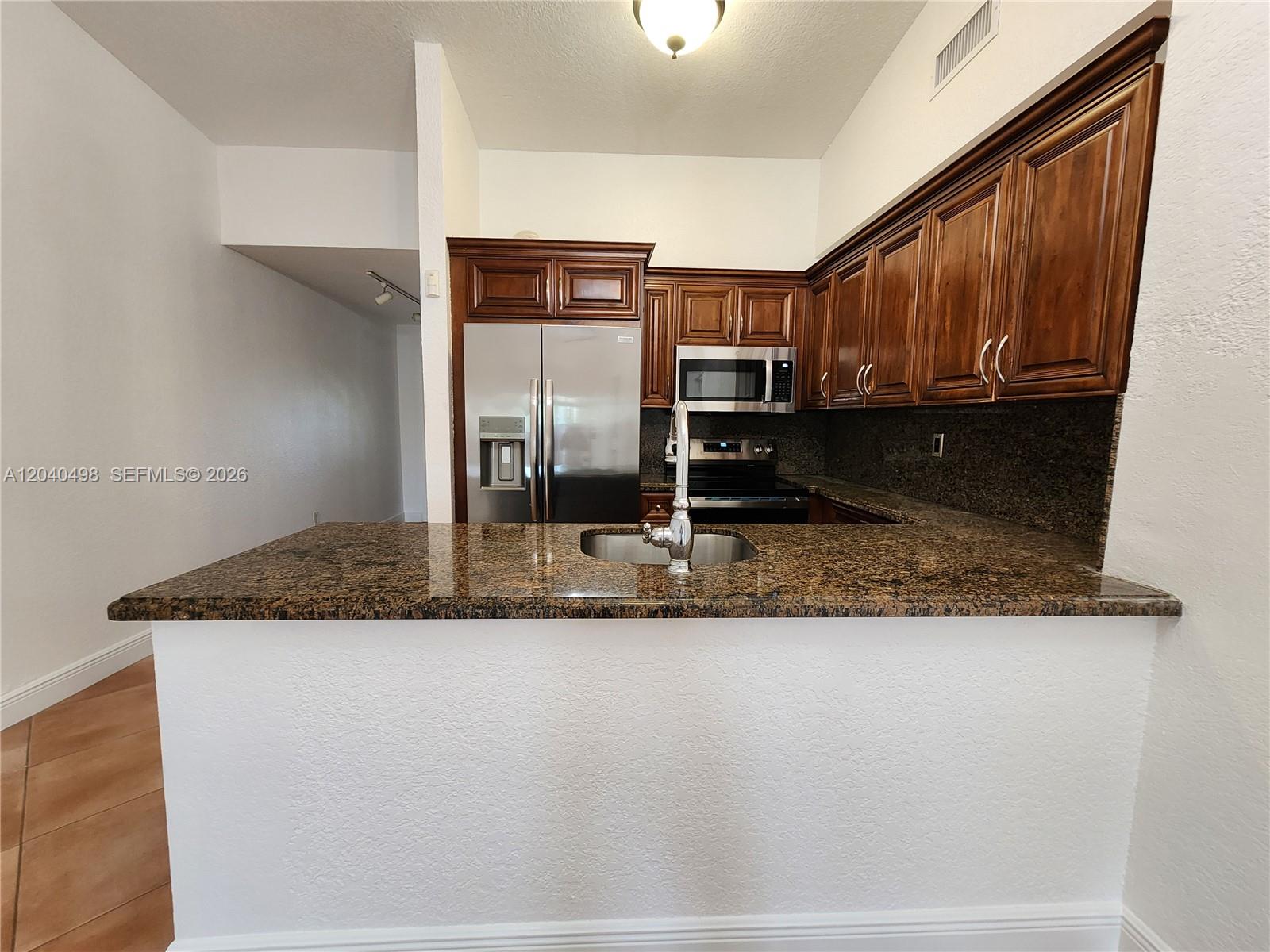 A kitchen features dark wood cabinets, granite countertops, stainless steel appliances, and a breakfast bar — 13412 SW 17th Terr Cir S, Miami FL 33175, MIAMI, FL