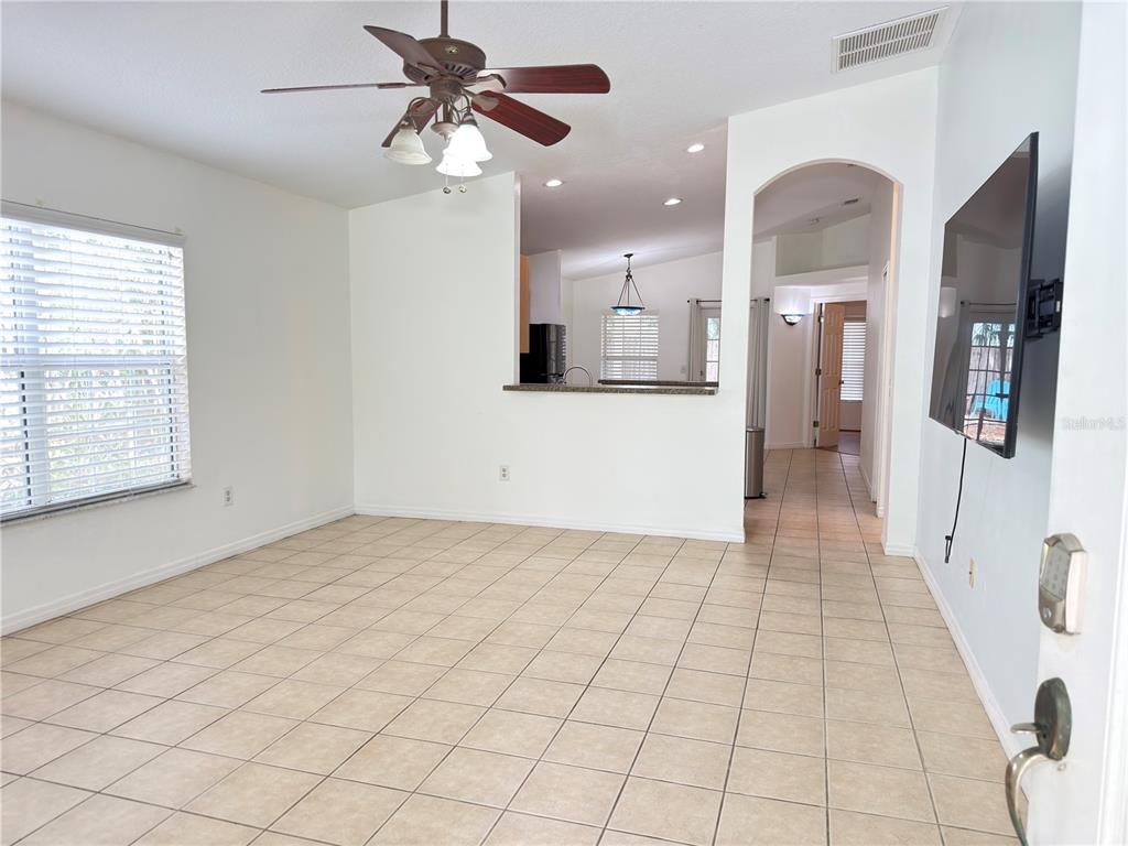 A living room with tile floors, a ceiling fan, and an opening to the kitchen — 414 ULELAH AVENUE, PALM HARBOR, FL