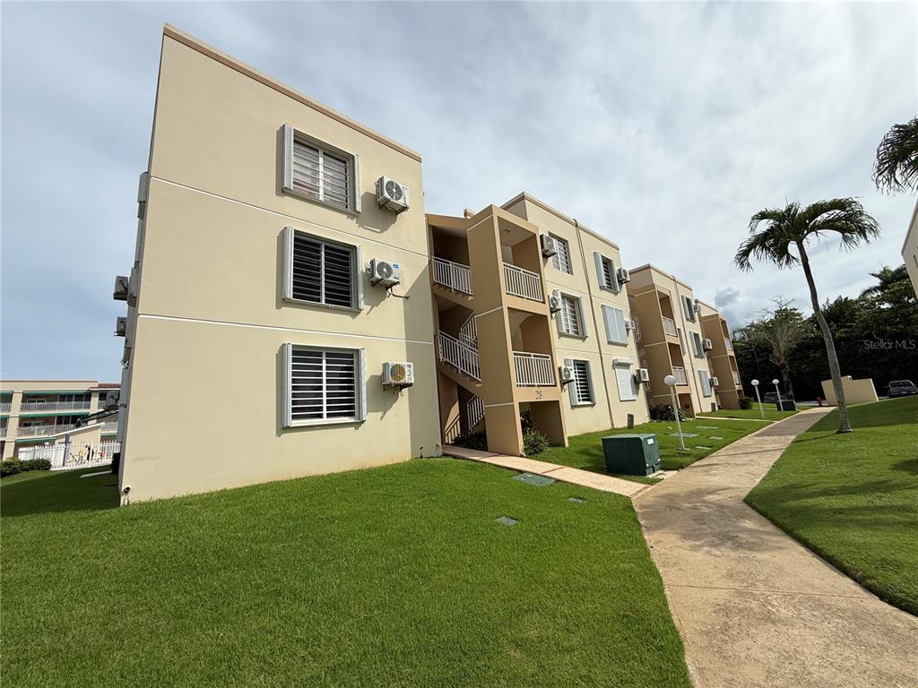 A multi-story tan apartment building with exterior staircases and a sidewalk on a grassy lawn — . CAMINO DE LAS PICUAS UNIT 2815, RIO GRANDE, PR