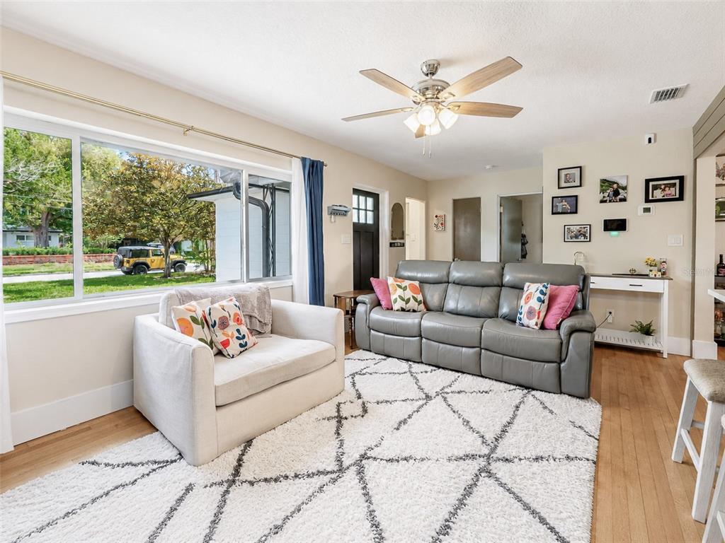 A living room features a gray leather sofa, a white armchair, and a geometric rug — 304 E JERSEY STREET, ORLANDO, FL