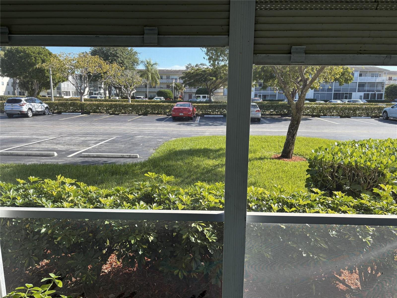View of a parking lot and apartment buildings from a screened-in porch — 91 Preston C # C, Boca Raton FL 33434, BOCA RATON, FL