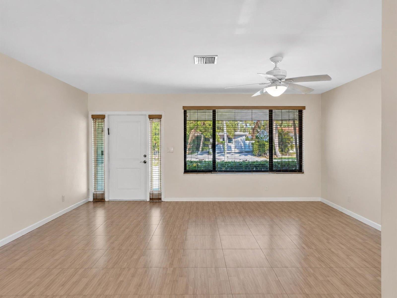 An empty room with light-colored walls, wood-look tile flooring, a ceiling fan, and a front door — 19321 NE 18th Place, Miami FL 33179, MIAMI, FL