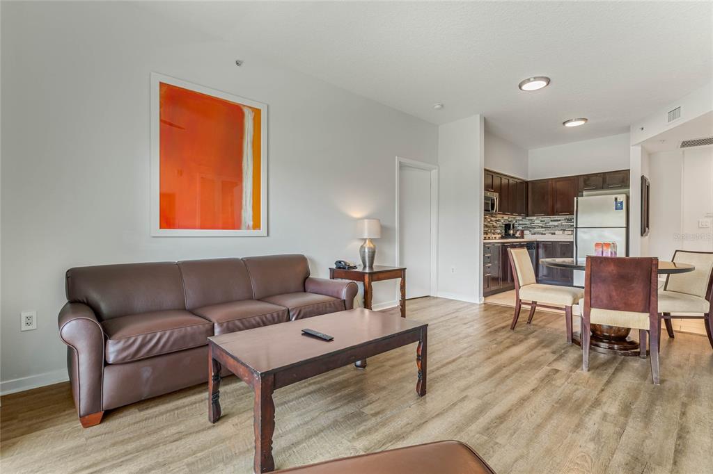 A living room with a brown leather sofa, coffee table, and adjacent dining area — 225 CELEBRATION PLACE UNIT 117, CELEBRATION, FL