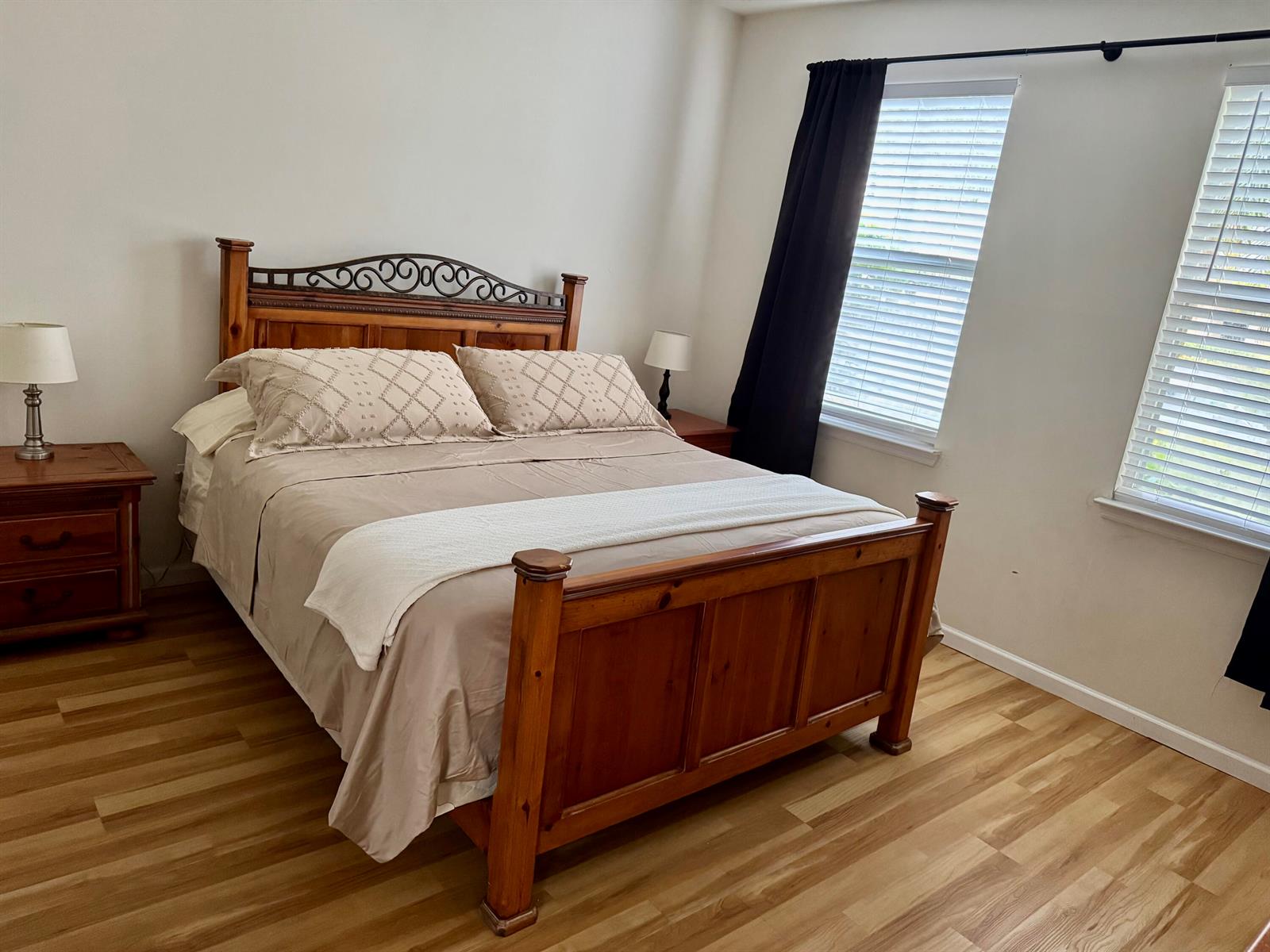 A bedroom features a wooden bed frame, two nightstands with lamps, and light wood flooring — 276 Murcia Drive # 111, Jupiter FL 33458, JUPITER, FL