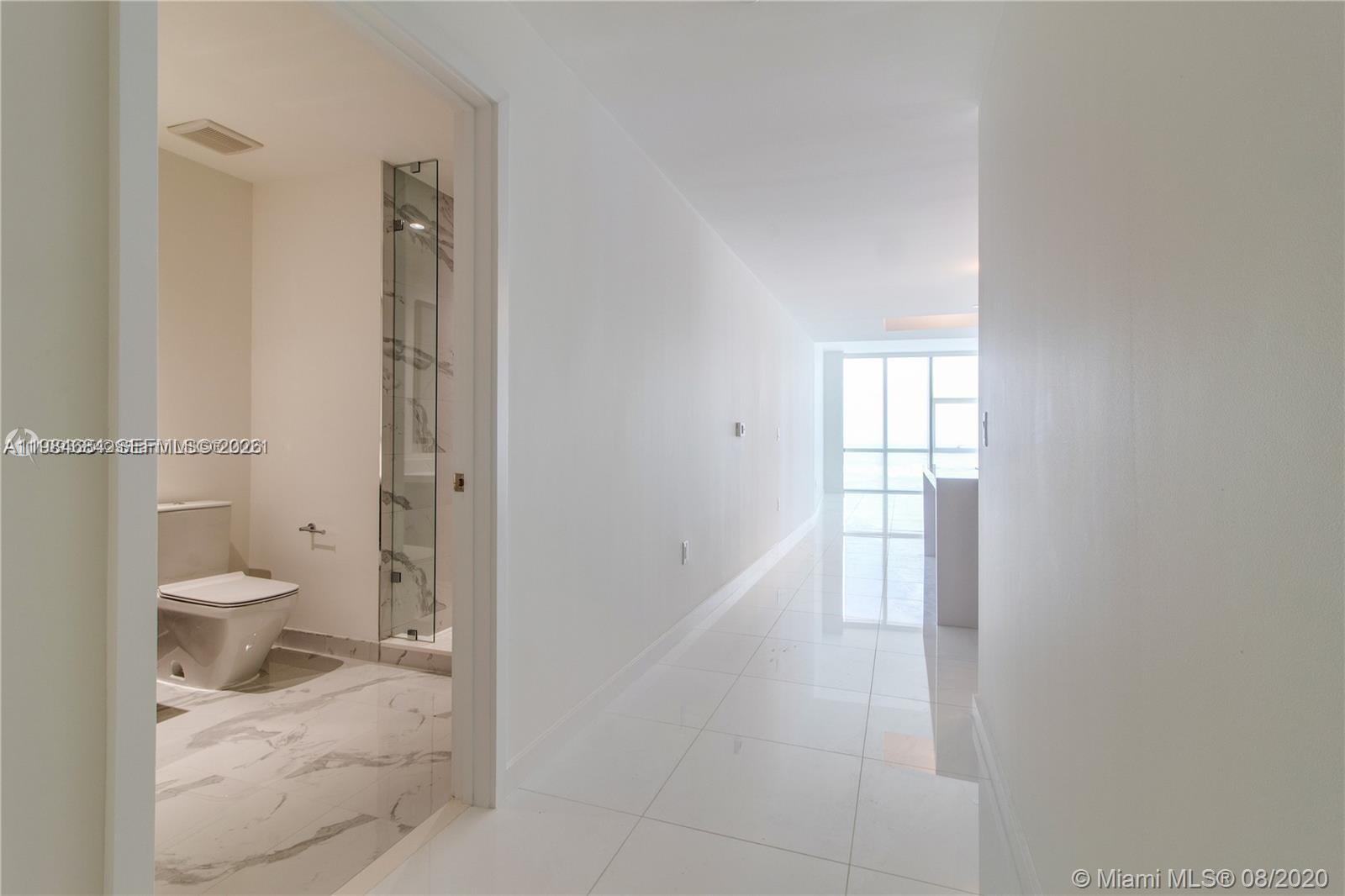 A hallway with white tile floors leads to a bright room with floor-to-ceiling windows — 851 NE 1st Ave # 3601, Miami FL 33132, MIAMI, FL