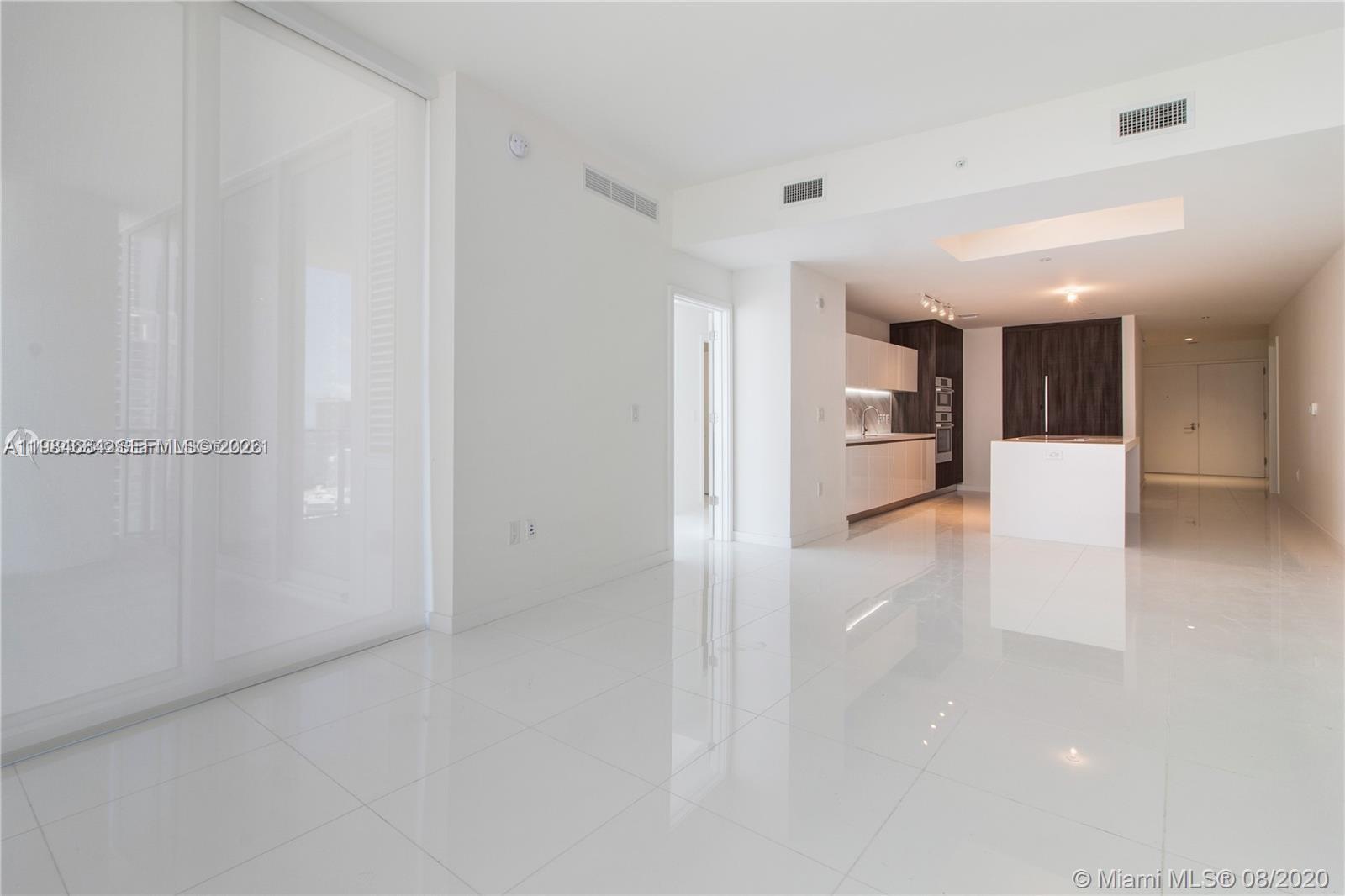 A modern, open-concept living area features white tile flooring, a kitchen island, and white cabinetry — 851 NE 1st Ave # 3601, Miami FL 33132, MIAMI, FL