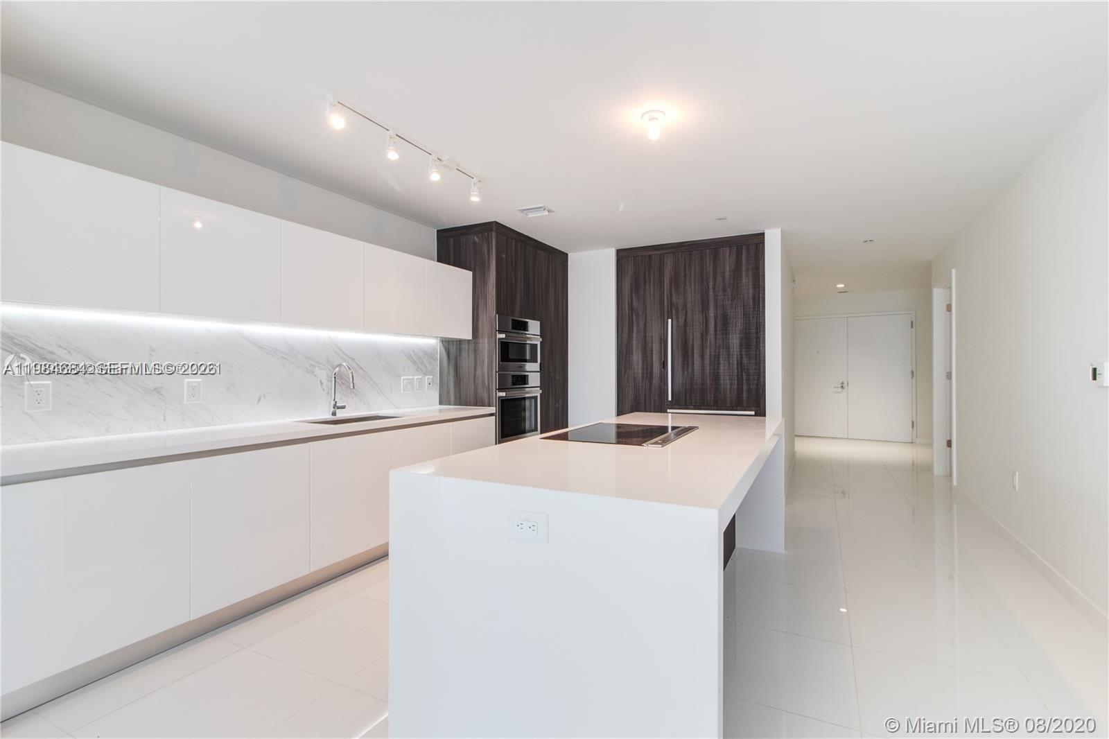 A modern kitchen features white cabinetry, a marble backsplash, and a large central island — 851 NE 1st Ave # 3601, Miami FL 33132, MIAMI, FL