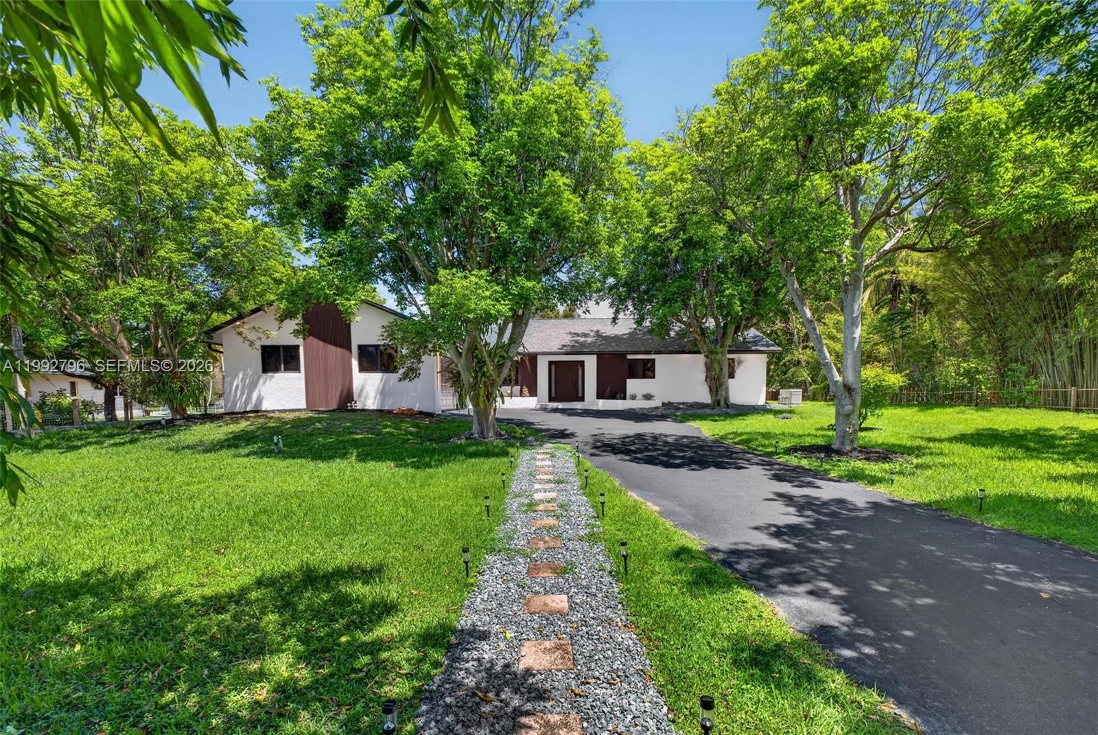 A single-story house with a white exterior, brown accents, and a paved driveway — 14755 SW 18th Ct, Davie FL 33325, DAVIE, FL