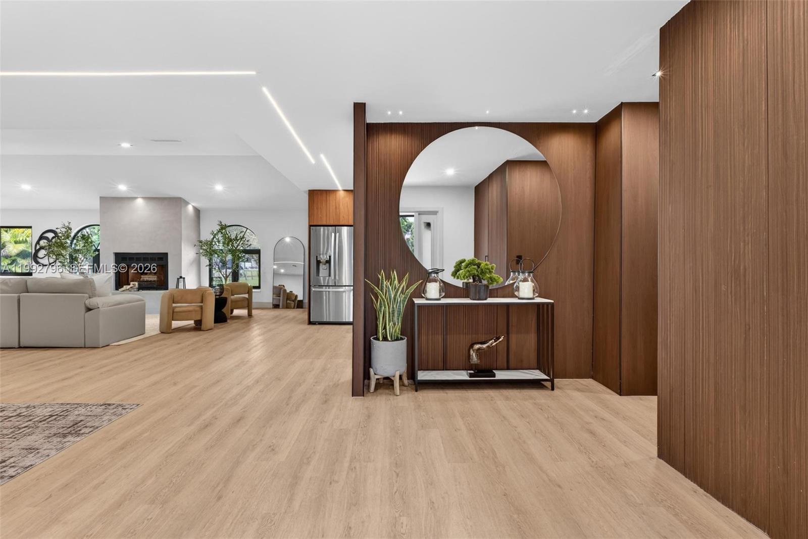 A modern living area features light wood flooring, a circular mirror, and wood-paneled walls — 14755 SW 18th Ct, Davie FL 33325, DAVIE, FL