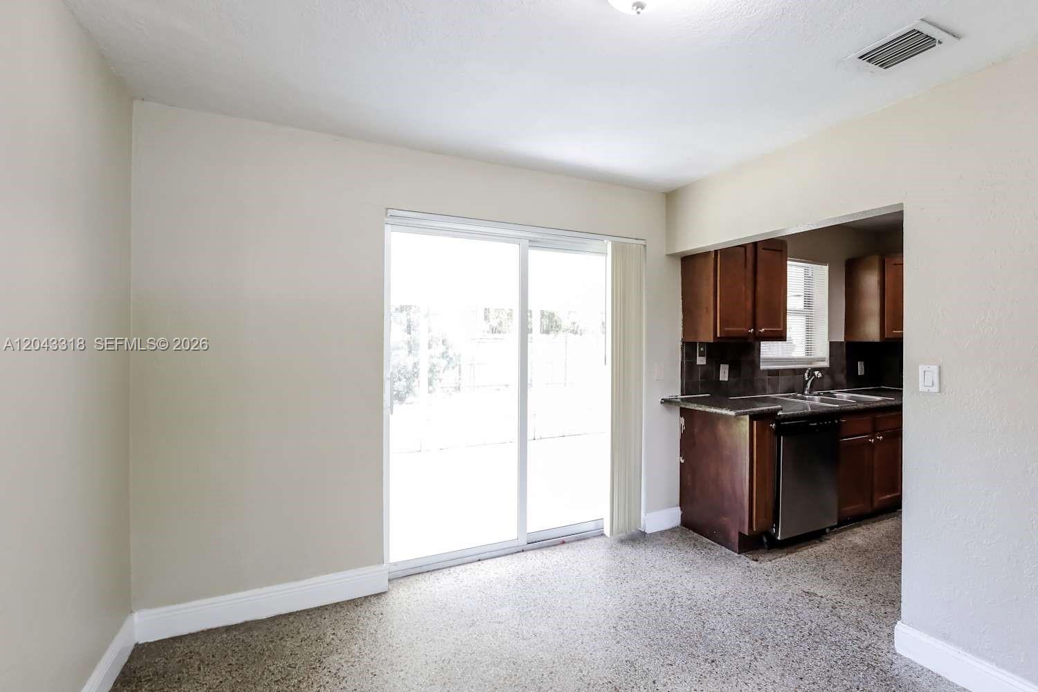A dining area with a sliding glass door leads into a kitchen with dark cabinetry — FORT LAUDERDALE, FL
