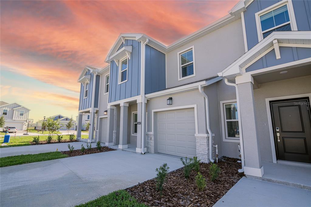 A two-story townhouse exterior with a gray garage, blue siding accents, and a concrete driveway — 2642 RUNNERS CIRCLE, CLERMONT, FL