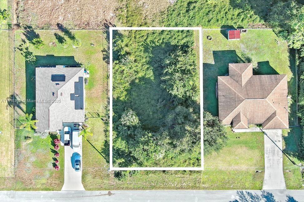 An aerial view shows a vacant, wooded rectangular lot situated between two existing residential houses — 341 Ranchito Ave, Lehigh Acres FL 33974, LEHIGH ACRES, FL