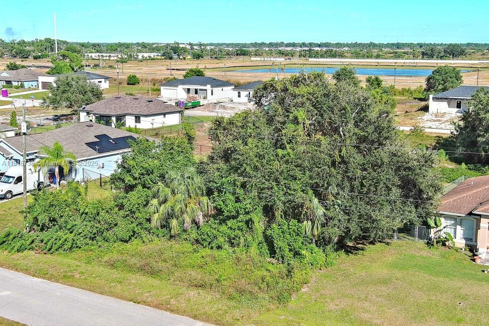 An aerial view shows a vacant, tree-covered lot situated between several residential houses — 341 Ranchito Ave, Lehigh Acres FL 33974, LEHIGH ACRES, FL