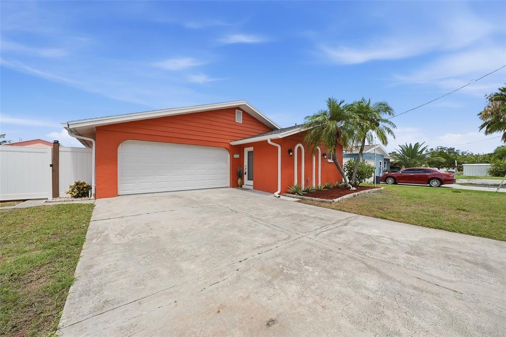 A bright orange single-story house features a white garage door and a concrete driveway — 13815 PLUMOSA AVENUE, HUDSON, FL