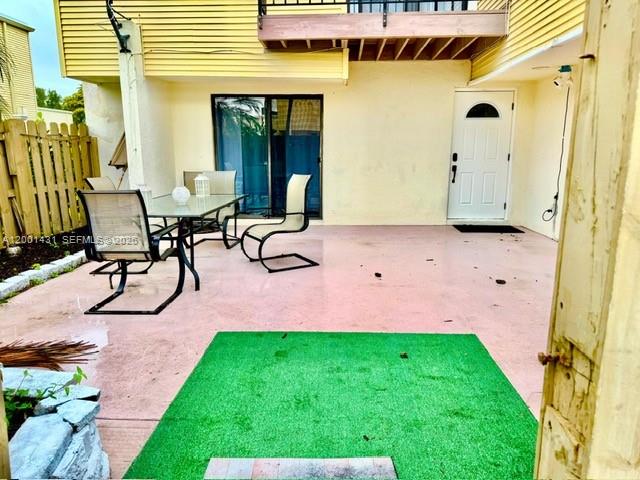 A patio features a dining set, a green rug, and a white door on a house — 1569 Shaker Cir, Wellington FL 33414, WELLINGTON, FL