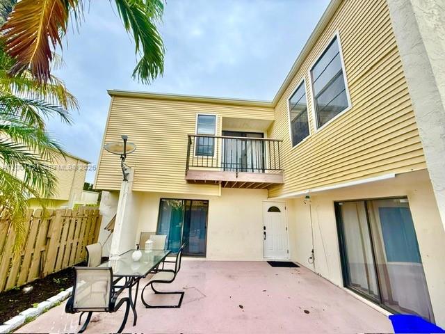 A patio with a dining set sits outside a two-story house with yellow siding — 1569 Shaker Cir, Wellington FL 33414, WELLINGTON, FL