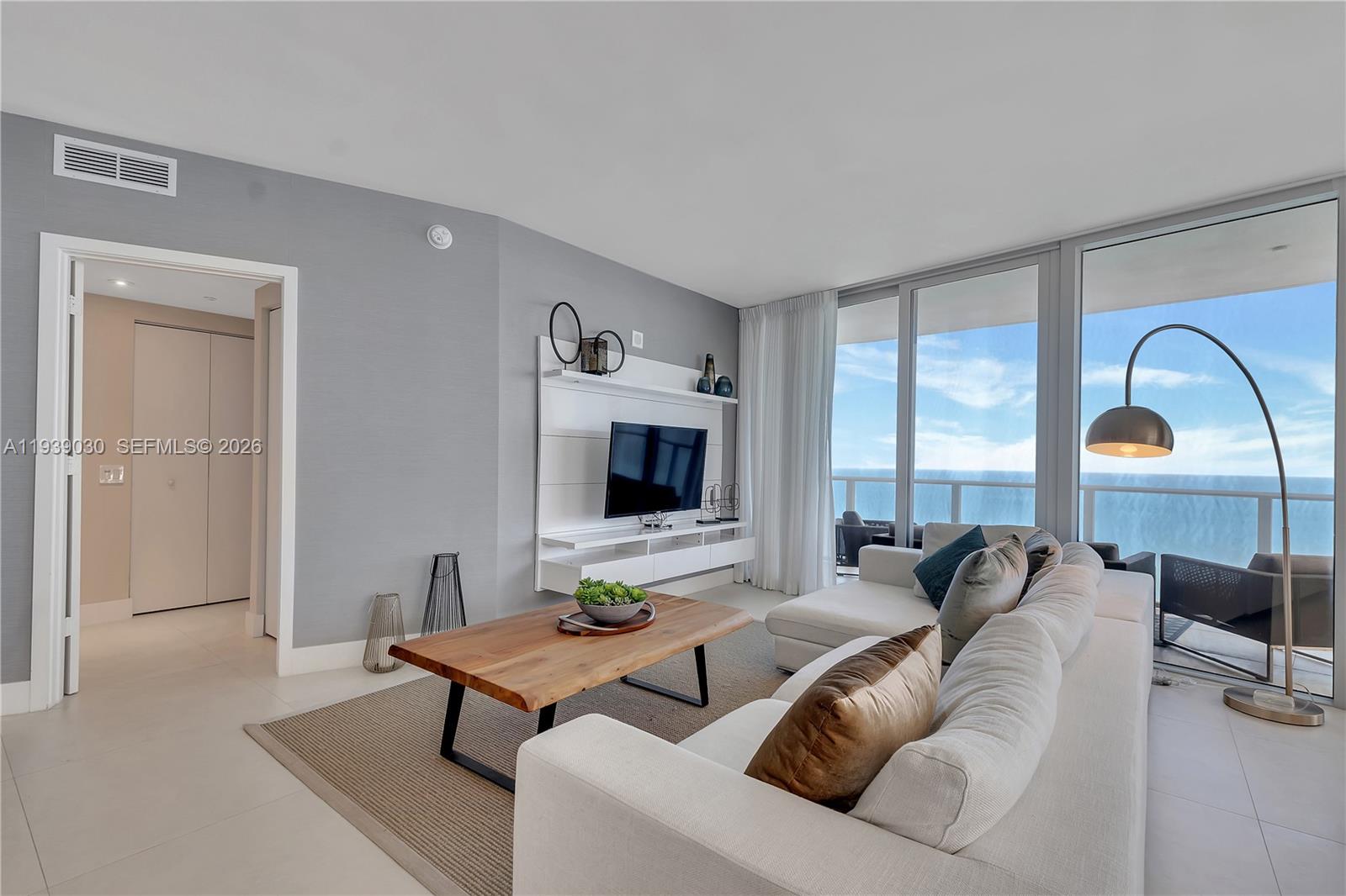A modern living room features a white media console, sectional sofa, and ocean views — 4111 S Ocean Dr # 3601, Hollywood FL 33019, HOLLYWOOD, FL
