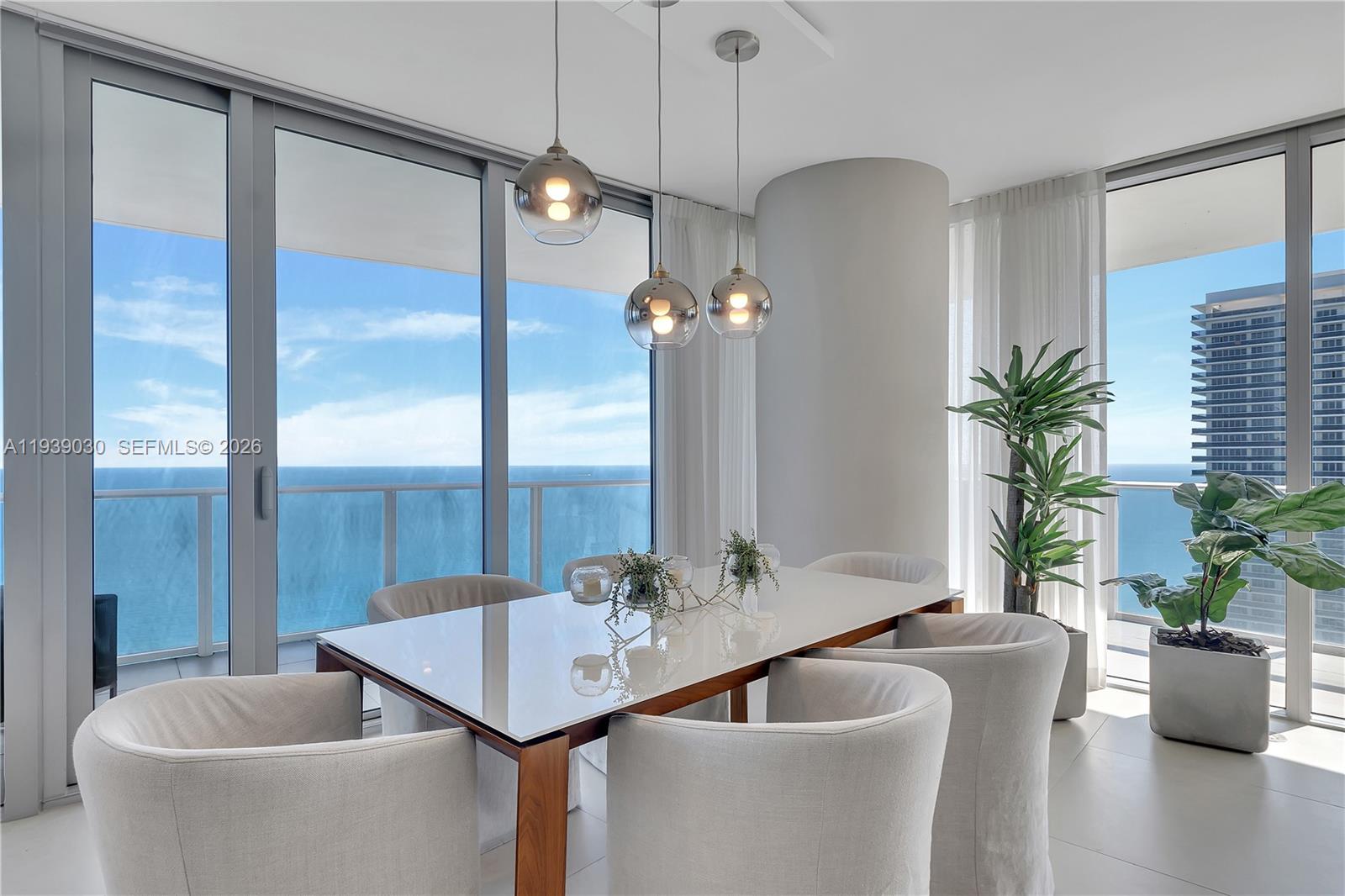 A dining room features a white table, upholstered chairs, pendant lights, and floor-to-ceiling ocean views — 4111 S Ocean Dr # 3601, Hollywood FL 33019, HOLLYWOOD, FL