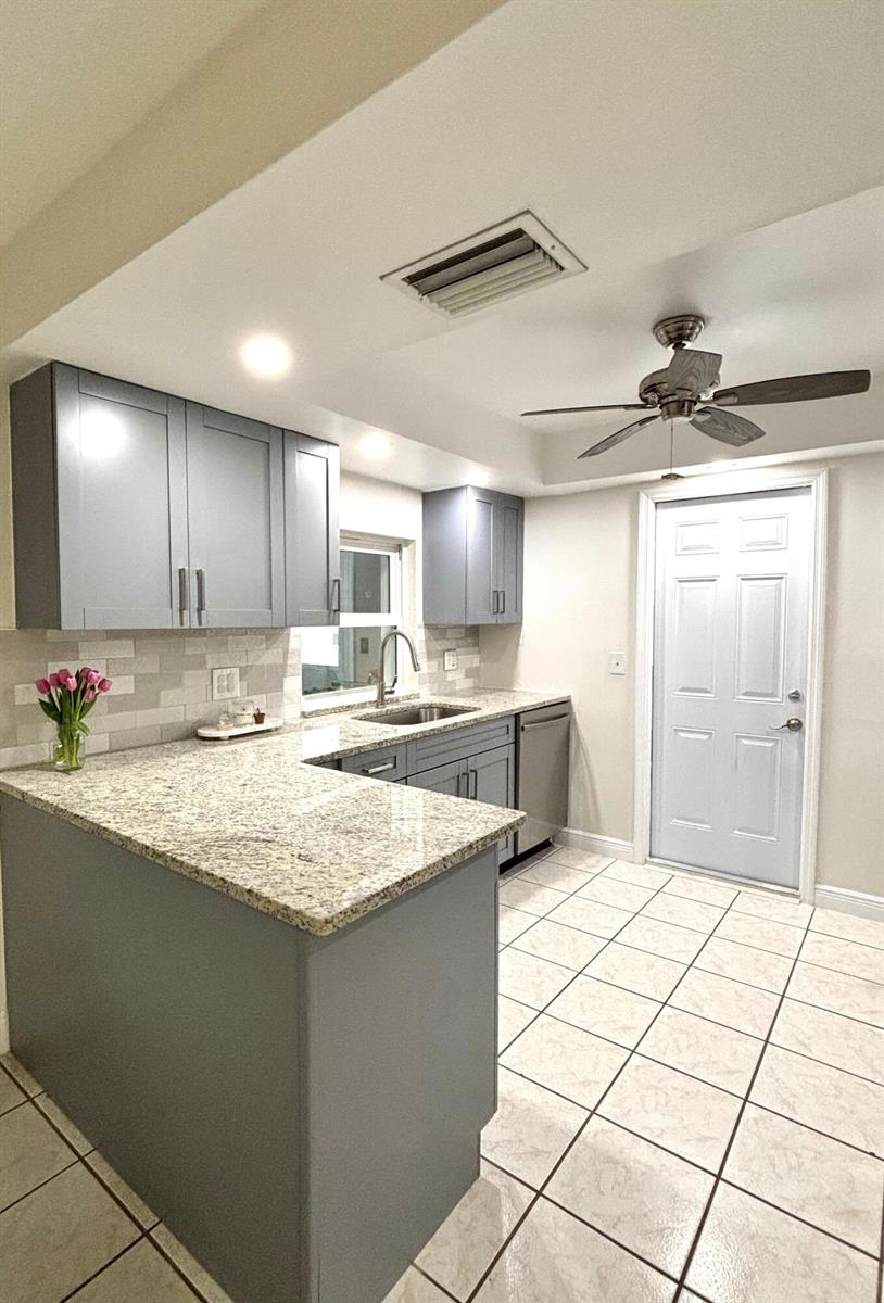 A kitchen features gray cabinets, granite countertops, a tile backsplash, and a ceiling fan — 1707 E Ironwood Ct Court E, FL 34677, FL