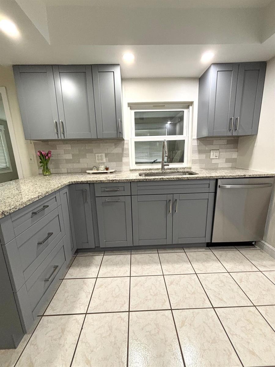 A kitchen features gray shaker cabinets, granite countertops, a tile backsplash, and light-colored floor tiles — 1707 E Ironwood Ct Court E, FL 34677, FL