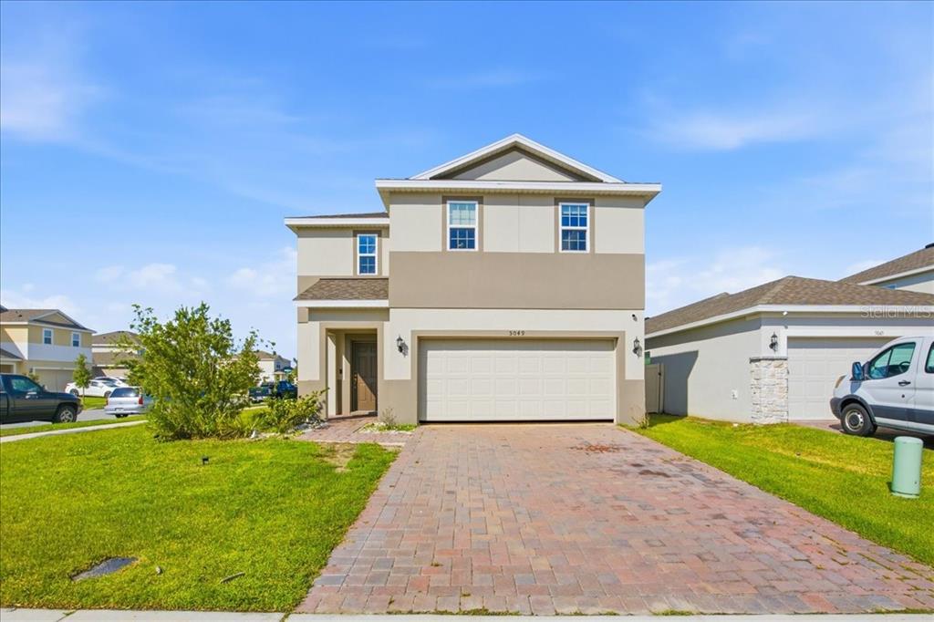 A two-story suburban house features a paved driveway, a two-car garage, and a front lawn — 5049 BLUE HAMMOCK COURT, KISSIMMEE, FL