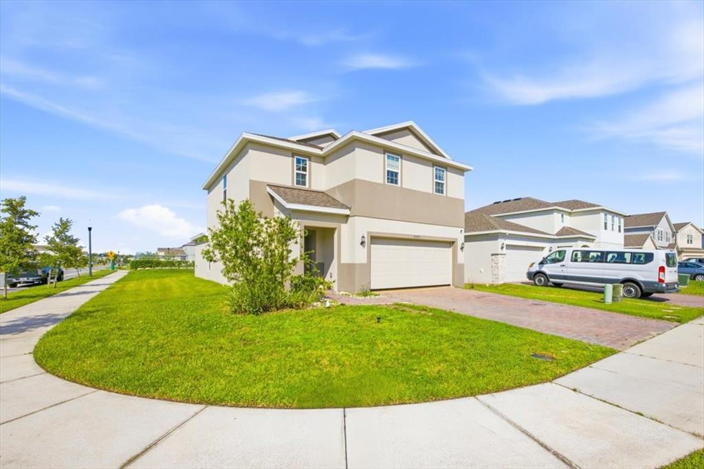 A two-story suburban house with a beige exterior, a two-car garage, and a front lawn — 5049 BLUE HAMMOCK COURT, KISSIMMEE, FL