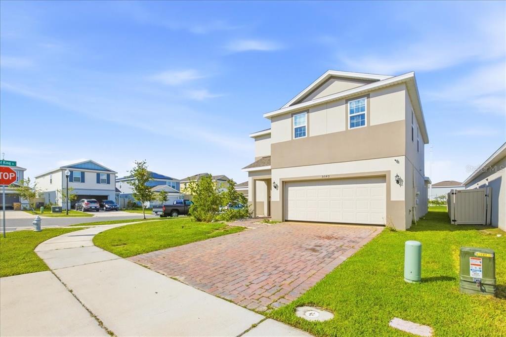 A two-story suburban house with a brick driveway and a two-car garage — 5049 BLUE HAMMOCK COURT, KISSIMMEE, FL