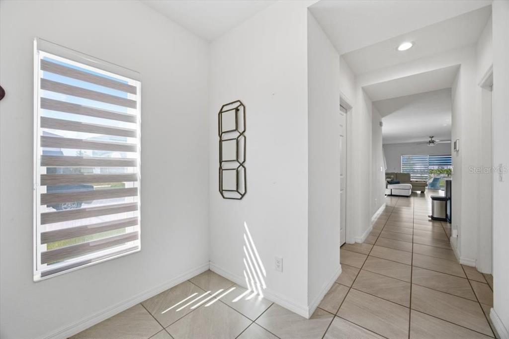 A bright entryway with tiled floors leads to a hallway overlooking a living area — 5049 BLUE HAMMOCK COURT, KISSIMMEE, FL