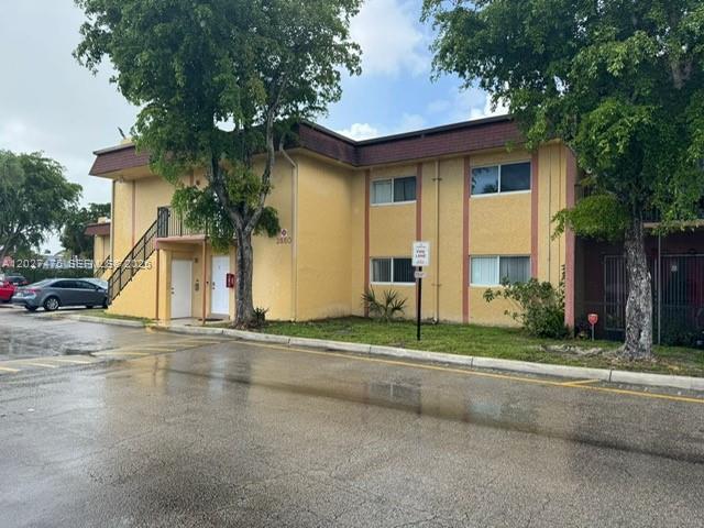A two-story yellow apartment building with a staircase and a wet parking lot — 2850 NW 55th Ave # 1D, Lauderhill FL 33313, LAUDERHILL, FL