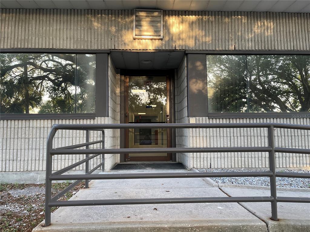 The exterior of a building features a glass entrance door, large windows, and a metal railing — 9555 SEMINOLE BOULEVARD UNIT 001, SEMINOLE, FL