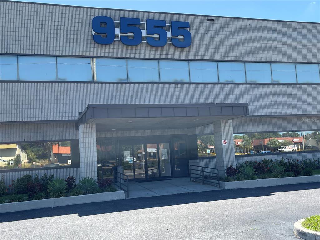 The exterior of a two-story commercial building features a prominent address number and entrance canopy — 9555 SEMINOLE BOULEVARD UNIT 001, SEMINOLE, FL