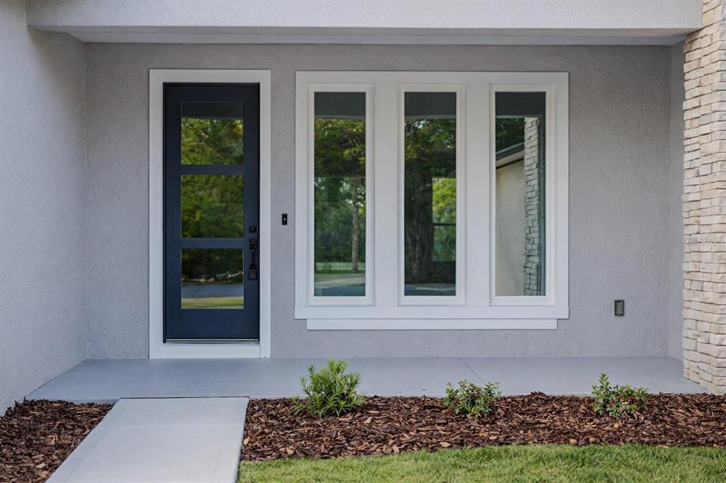 A gray exterior wall features a dark blue front door and a three-pane window — 23 BANNER LANE, PALM COAST, FL