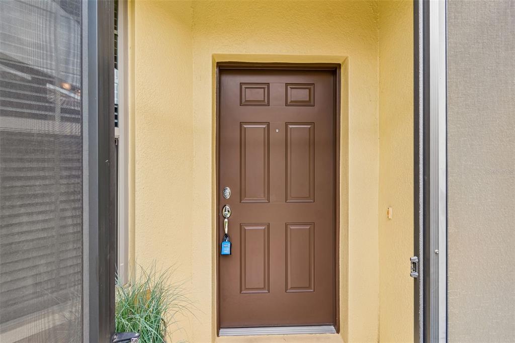 A brown front door with a lockbox is set within a yellow stucco entryway — 322 MYSTIC FALLS DRIVE, APOLLO BEACH, FL