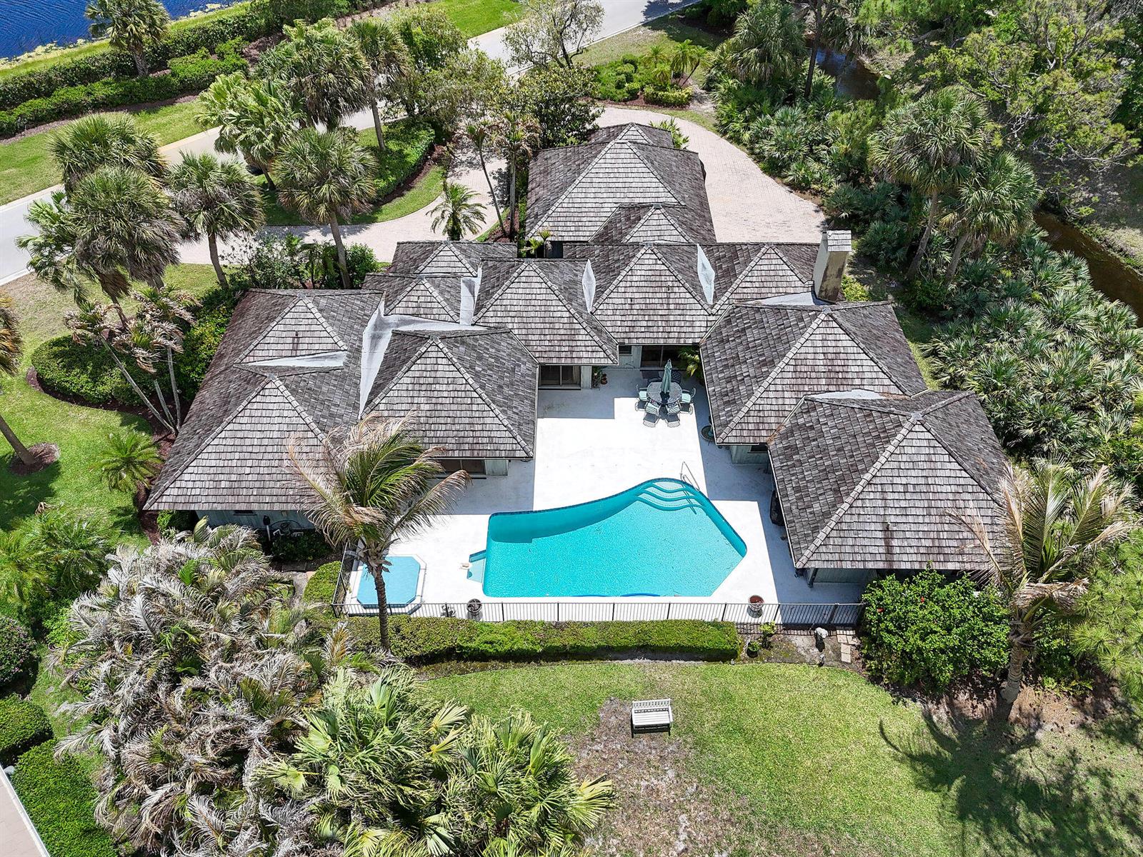 An aerial view of a house with a shingled roof, pool, and surrounding landscaping — 6980 SE Winged Foot Drive, Stuart FL 34997, STUART, FL