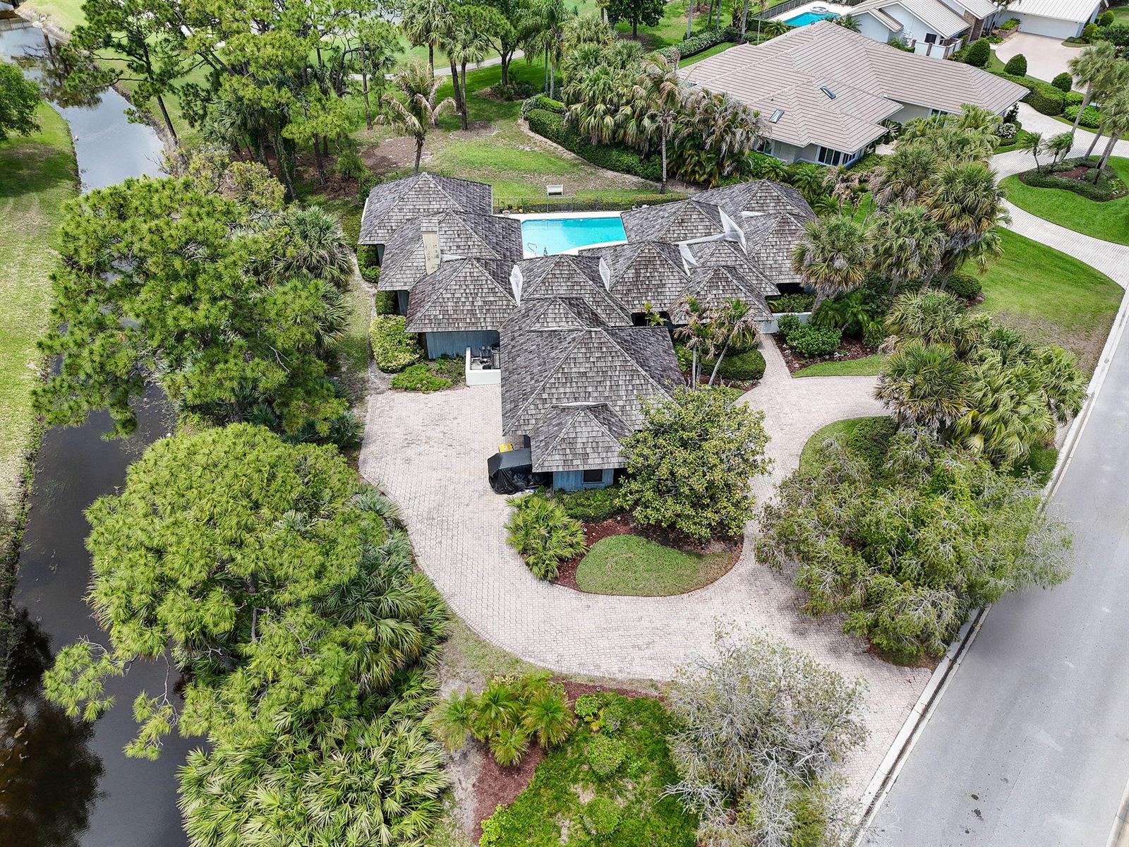 An aerial view shows a house with a shingled roof, pool, and circular driveway — 6980 SE Winged Foot Drive, Stuart FL 34997, STUART, FL
