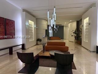 A modern lobby features a curved orange sofa, two dark chairs, and a hanging light fixture — 9066 SW 73rd Ct # 806, Miami FL 33156, MIAMI, FL