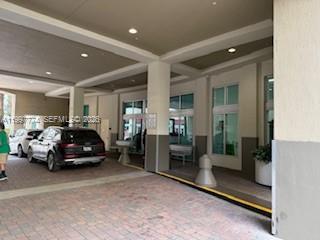 A covered driveway entrance with a brick floor leads to a building with glass windows — 9066 SW 73rd Ct # 806, Miami FL 33156, MIAMI, FL