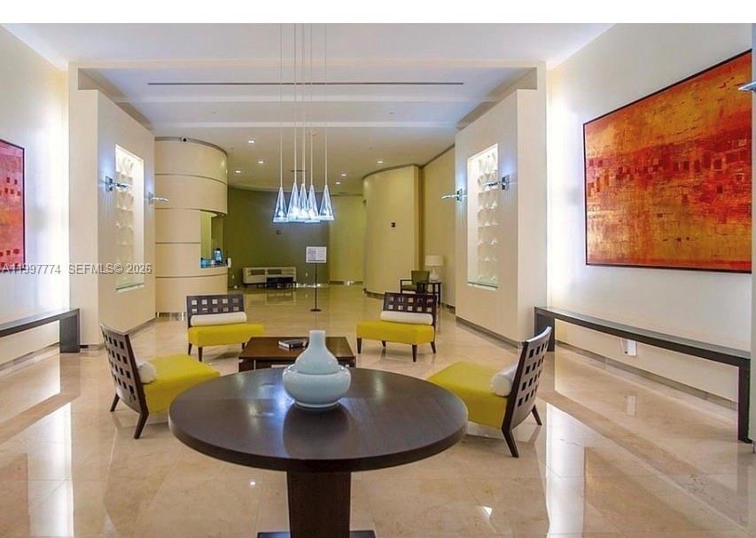 A modern lobby features yellow armchairs, a round table, and large abstract art on walls — 9066 SW 73rd Ct # 806, Miami FL 33156, MIAMI, FL