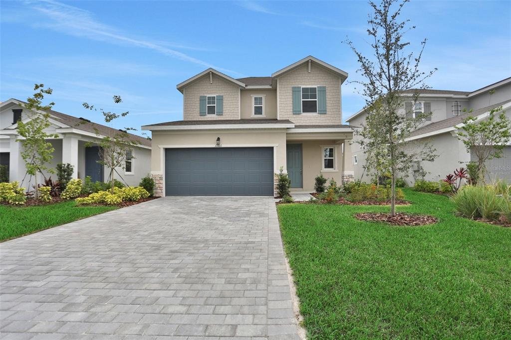 A two-story suburban house features a gray garage, beige siding, and a paved driveway — 13461 TURNLEAF BOULEVARD, PUNTA GORDA, FL