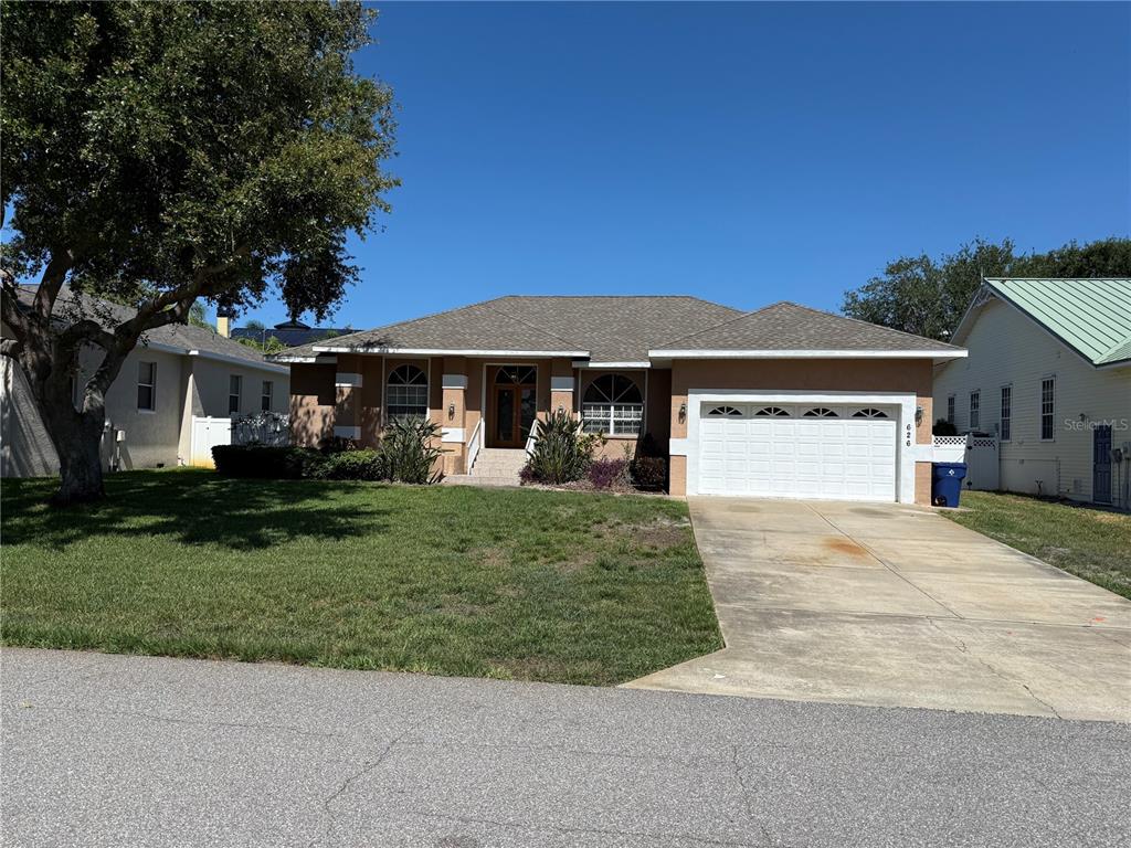 A single-story tan house with a white garage door and a concrete driveway — 626 7TH AVENUE N, TIERRA VERDE, FL