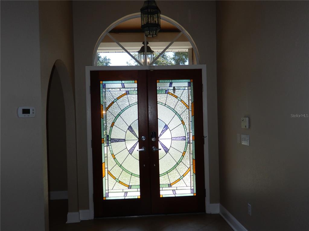 A foyer features double wooden doors with stained glass inserts and an arched transom window — 626 7TH AVENUE N, TIERRA VERDE, FL