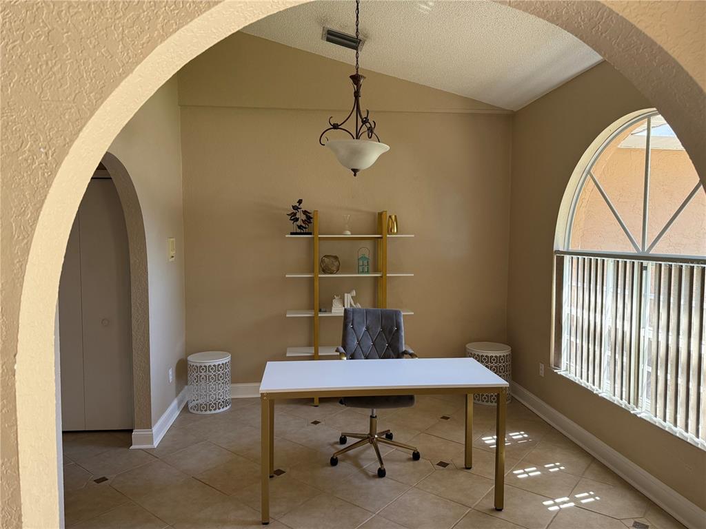 A home office features a white desk, a grey chair, and a gold-framed bookshelf — 626 7TH AVENUE N, TIERRA VERDE, FL