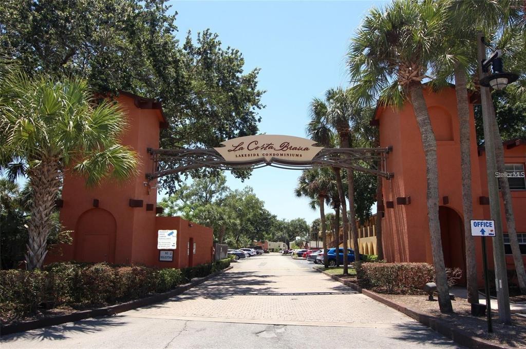 The entrance to La Costa Brava Lakeside Condominiums features two orange stucco towers and signage — 772 E MICHIGAN STREET UNIT 70, ORLANDO, FL