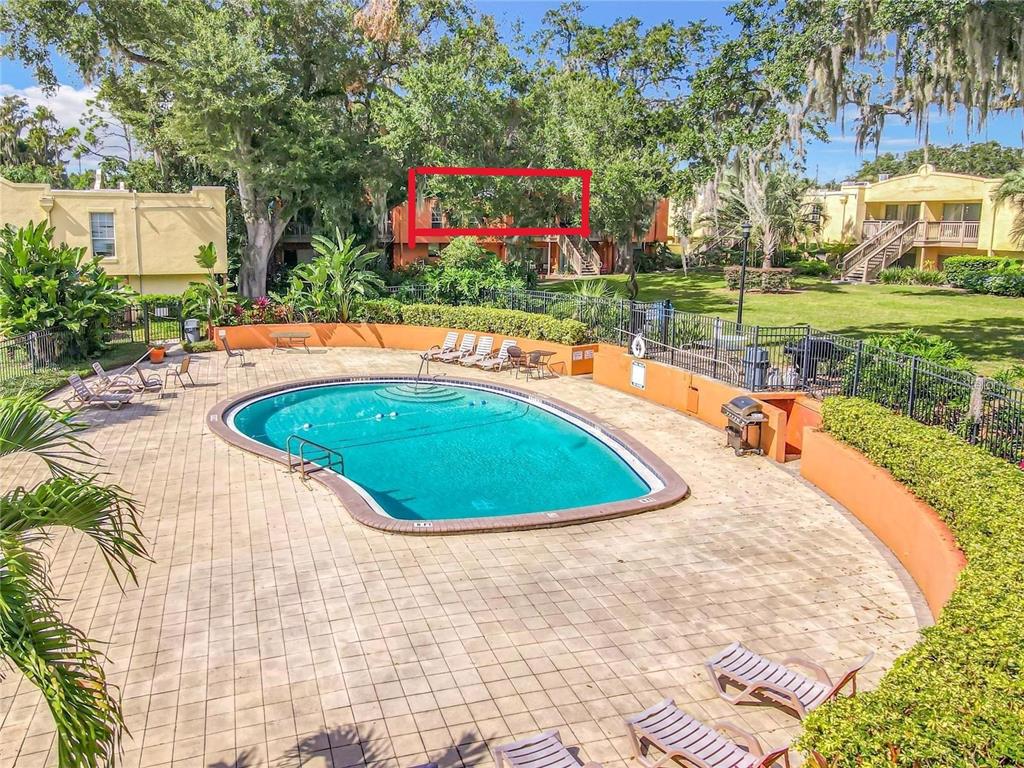 A swimming pool with lounge chairs sits in front of a multi-story apartment building — 772 E MICHIGAN STREET UNIT 70, ORLANDO, FL